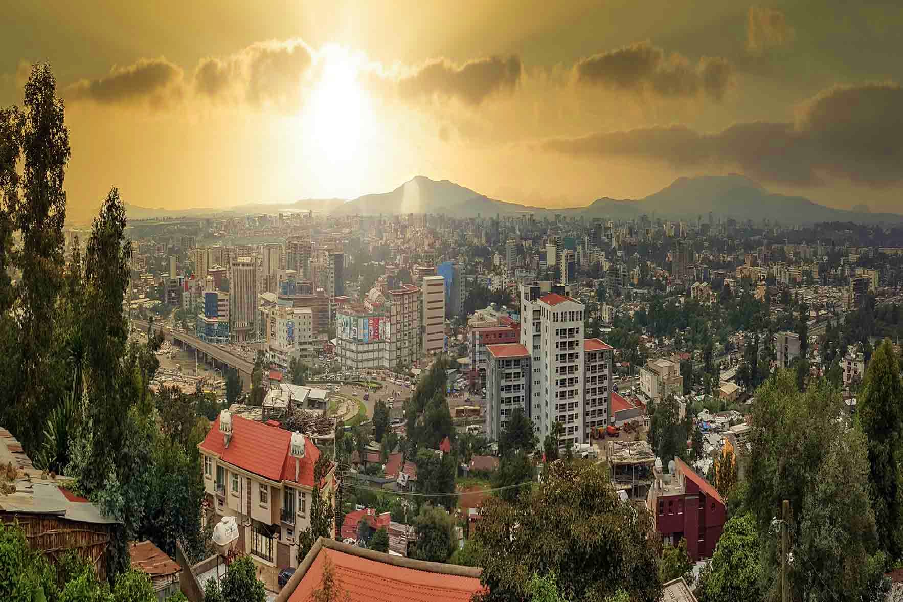Ethiopia Visa Aerial view of Addis Ababa skyline with mountains in background under golden sunlight, showing dense urban development and cy
